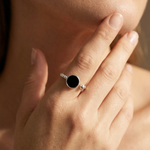 Close-up of a hand wearing a silver ring with a black gemstone.
