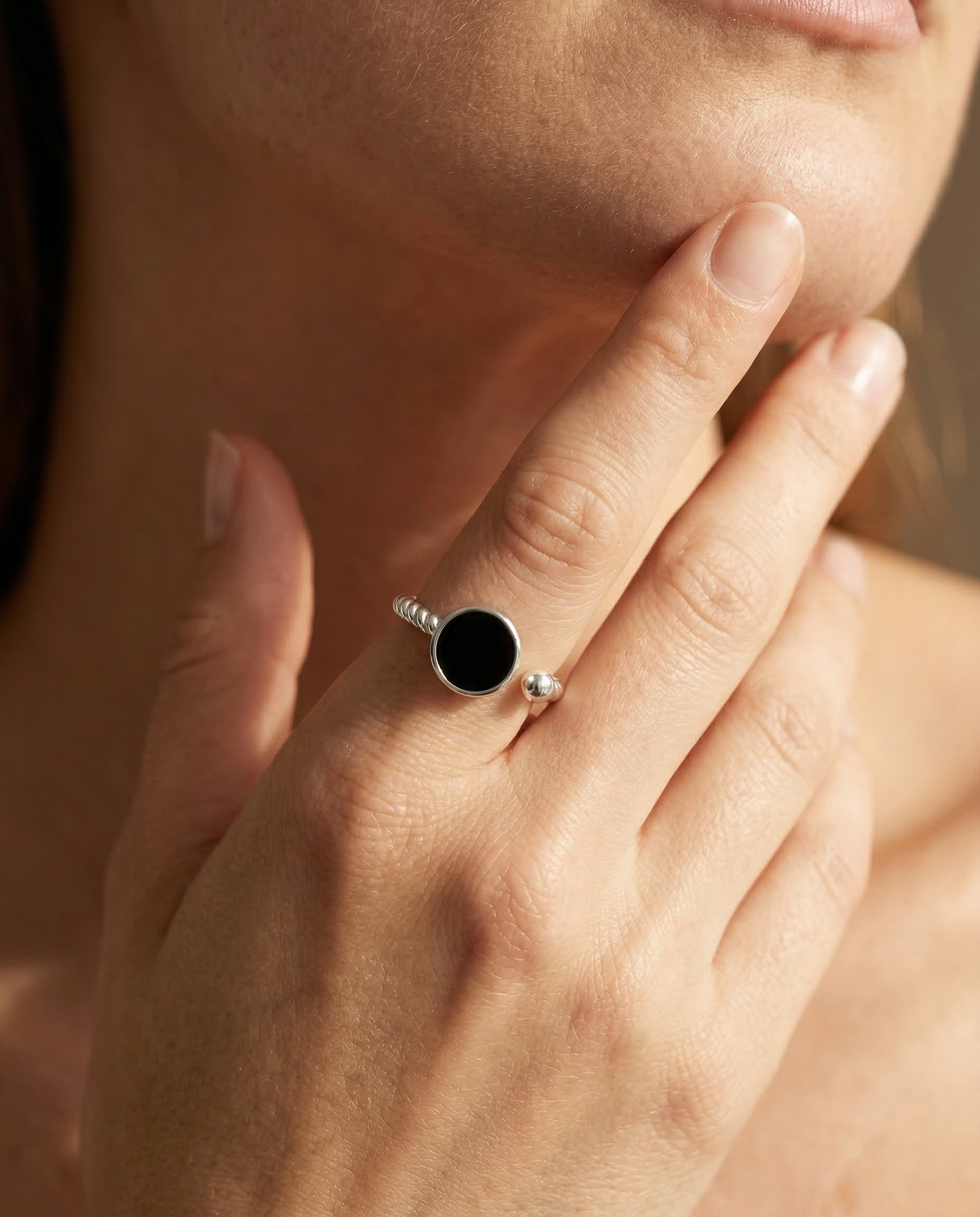 Close-up of a hand wearing a silver ring with a black gemstone.