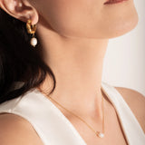 model wearing a  single white pearl pendant on a thin gold chain