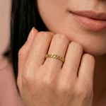 closeup of a model wearing a  gold-plated ring with a chain-inspired design, displaying a sleek, polished surface