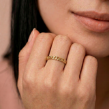 closeup of a model wearing a  gold-plated ring with a chain-inspired design, displaying a sleek, polished surface