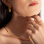 close up of a model wearing 2 delicate rings and a statement necklace