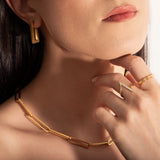 close up of a model wearing 2 delicate rings and a statement necklace