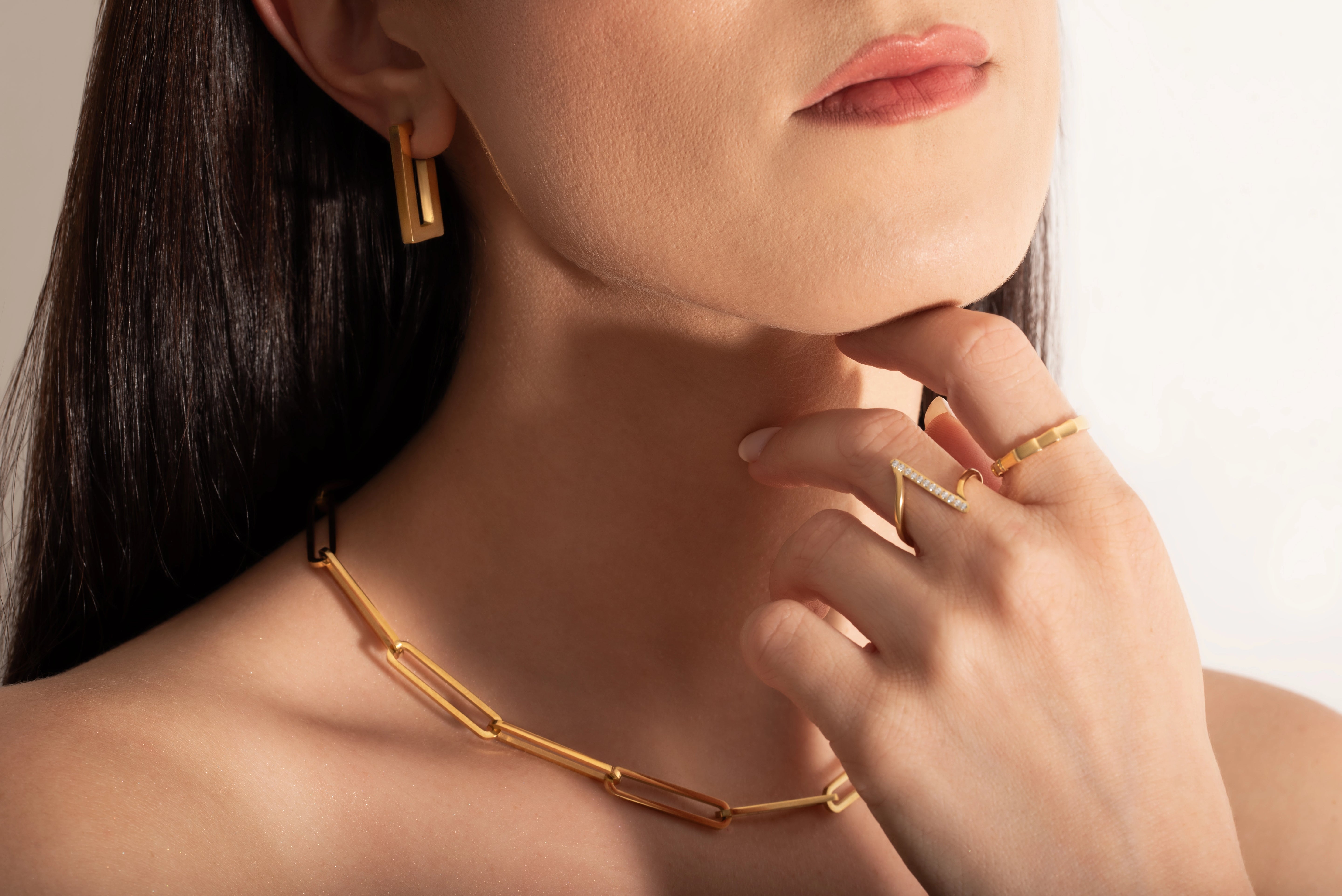 close up of a model wearing 2 delicate rings and a statement necklace