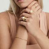 Close-up of a person wearing gold jewelry on a plain background