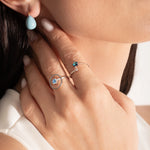 close up of a model wearing 2 beautiful sterling silver rings with blue gemstones