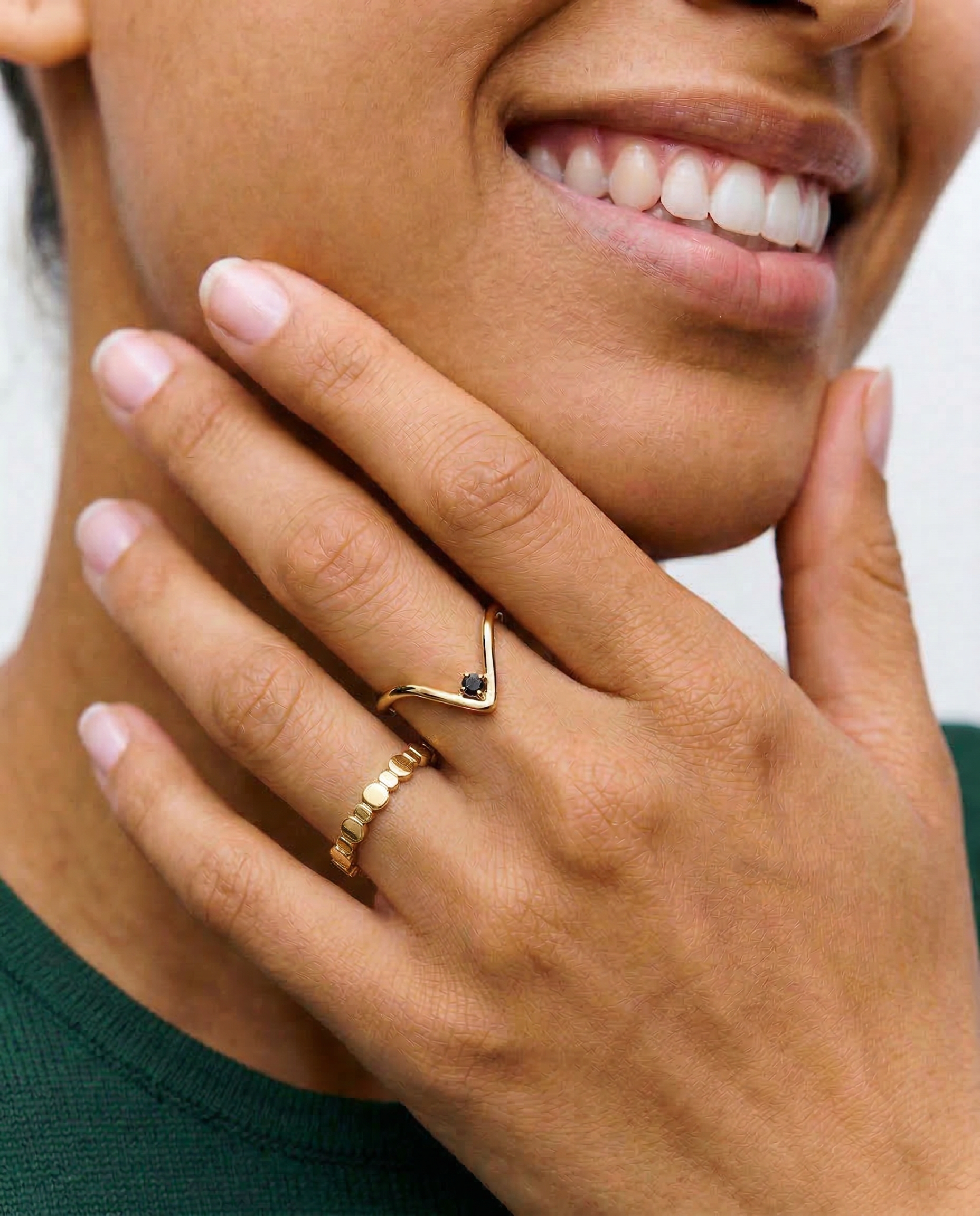 model wearing A gold-plated ring with an angular design and a black crystal set in a V-formation on a white background.
