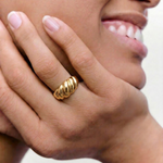 model wearing a gold-plated stainless steel ring with a textured, wave-like design