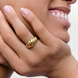 model wearing a gold-plated stainless steel ring with a textured, wave-like design