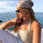 Woman sitting by the ocean wearing multiple gold plated jewellery