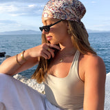 Woman sitting by the ocean wearing multiple gold plated jewellery