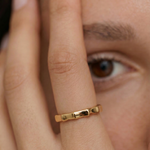 close up of a model wearing a gold-plated ring with a textured surface designed to mimic bamboo segments