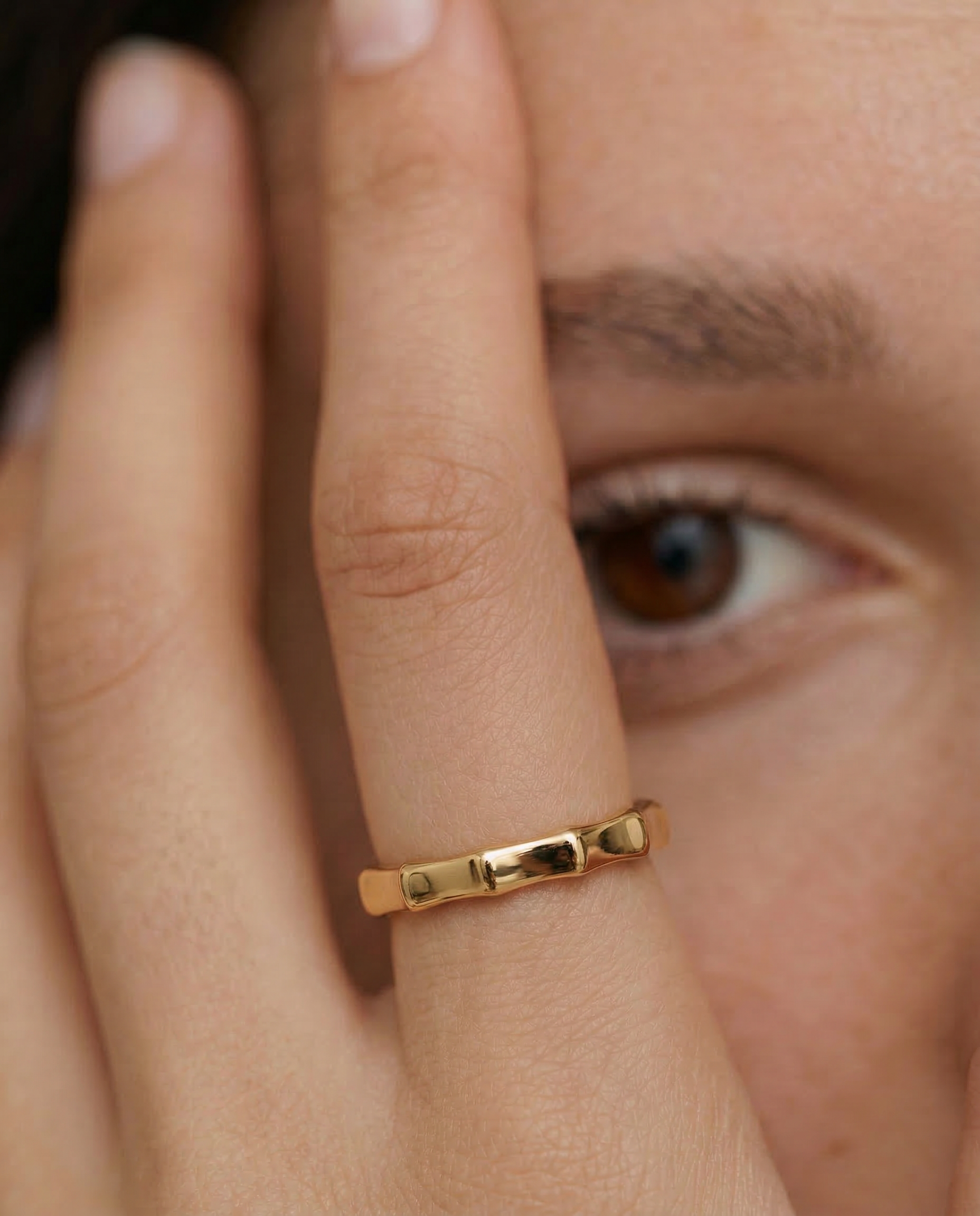 close up of a model wearing a gold-plated ring with a textured surface designed to mimic bamboo segments