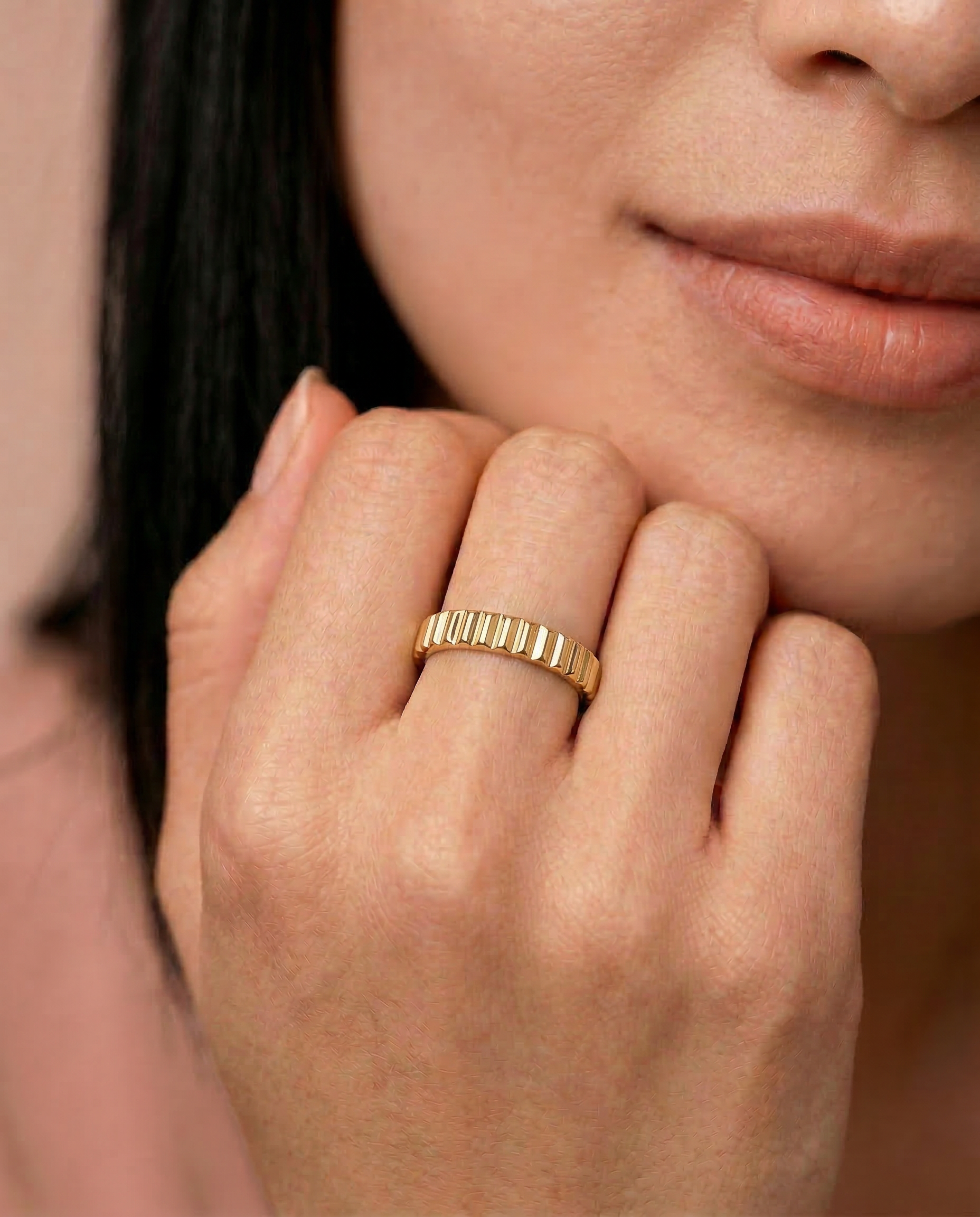 close up of a female model wearing a gold-plated band ring with fluted edges