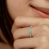 Close-up of a hand wearing a minimalist gold band with a partial pavé of turquoise stones 