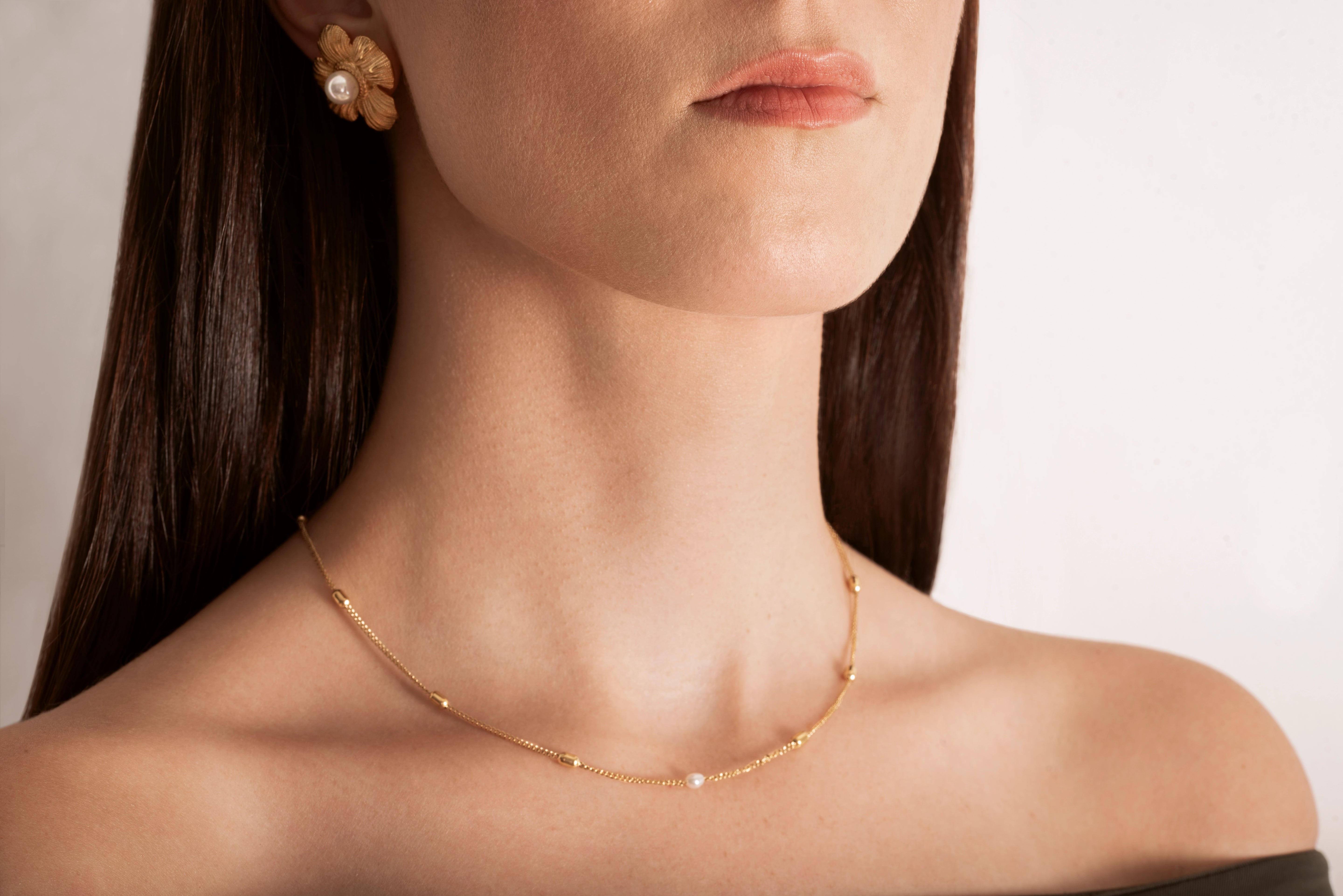 model wearing a gold-plated curb chain necklace with rectangular stations and a single pearl accent