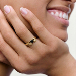 close up of a model wearing a statement gold plated ring with 2 hands holding a black heart