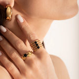 female model wearing 2 gold-plated Claddagh ring with a heart-shaped black gemstone, featuring two hands holding a heart and a crown on top.