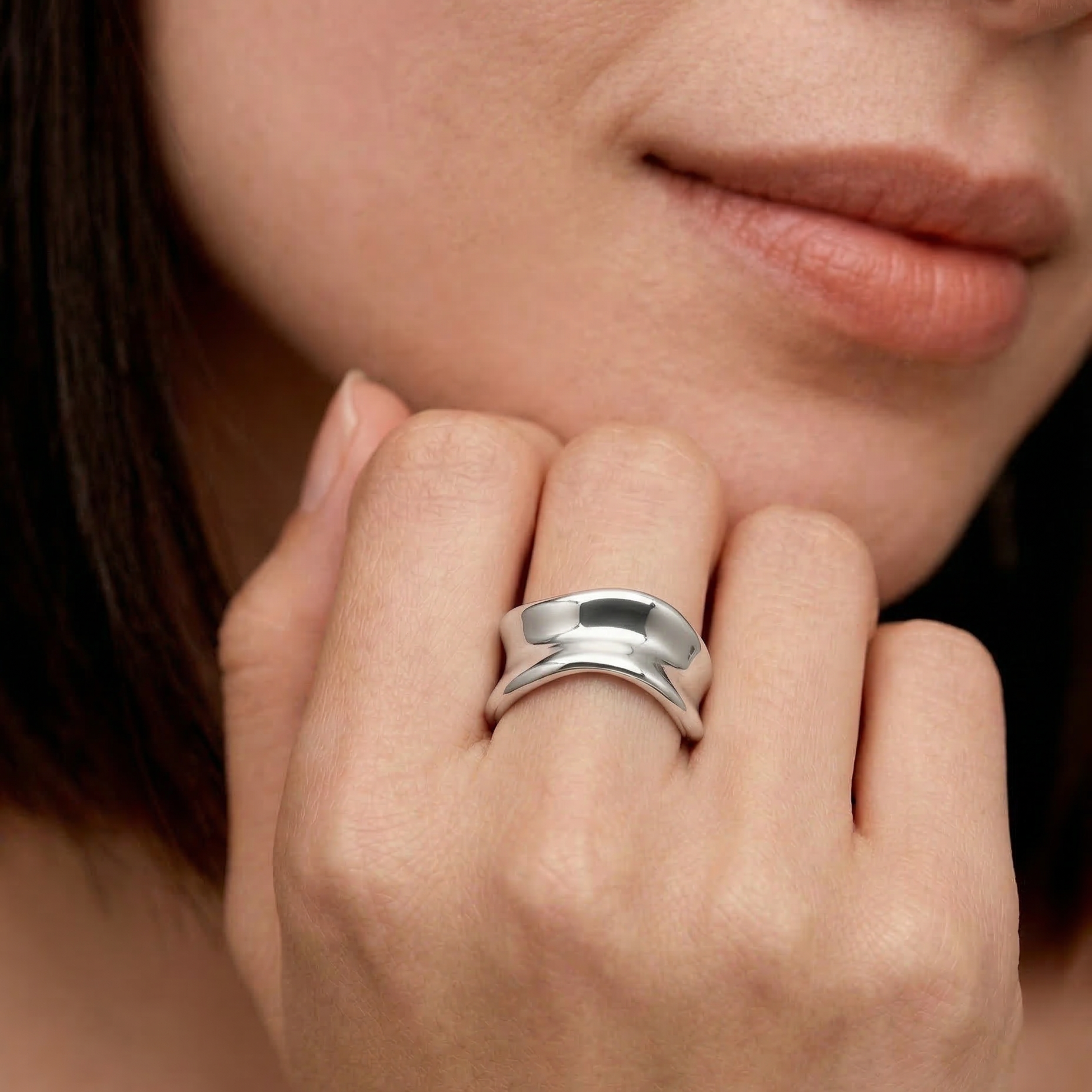 model wearing a sterling silver, asymmetrical, open-ended ring with a smooth, polished surface.