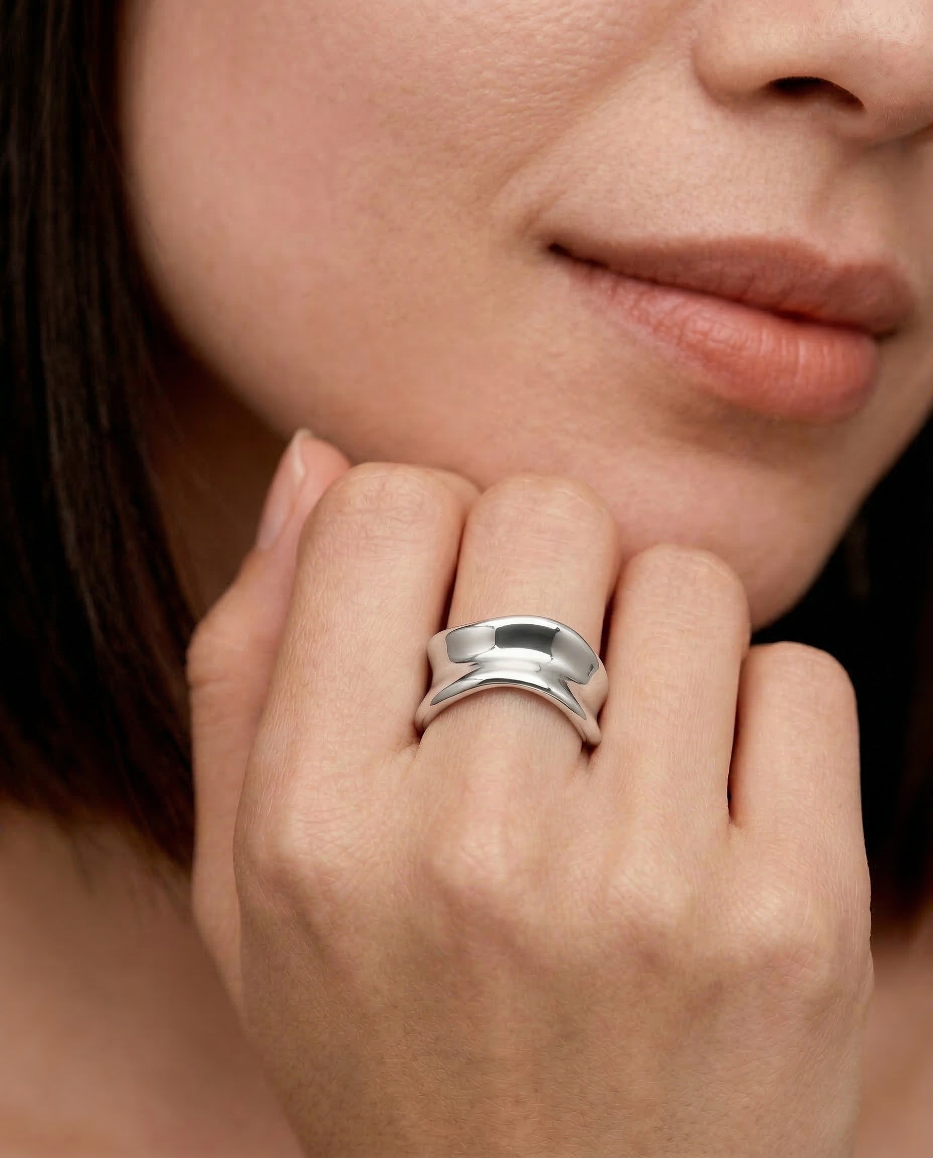model wearing a sterling silver, asymmetrical, open-ended ring with a smooth, polished surface.