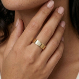 Close-up of a hand wearing a gold ring with a circular design and small stones.