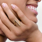 model wearing a contemporary gold-plated ring with an asymmetric design featuring a sleek bar adorned with a line of sparkling stones