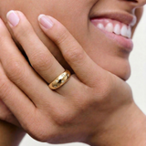 model wearing a gold-plated ring with a smooth, domed surface adorned with five star-shaped bezels containing crystals