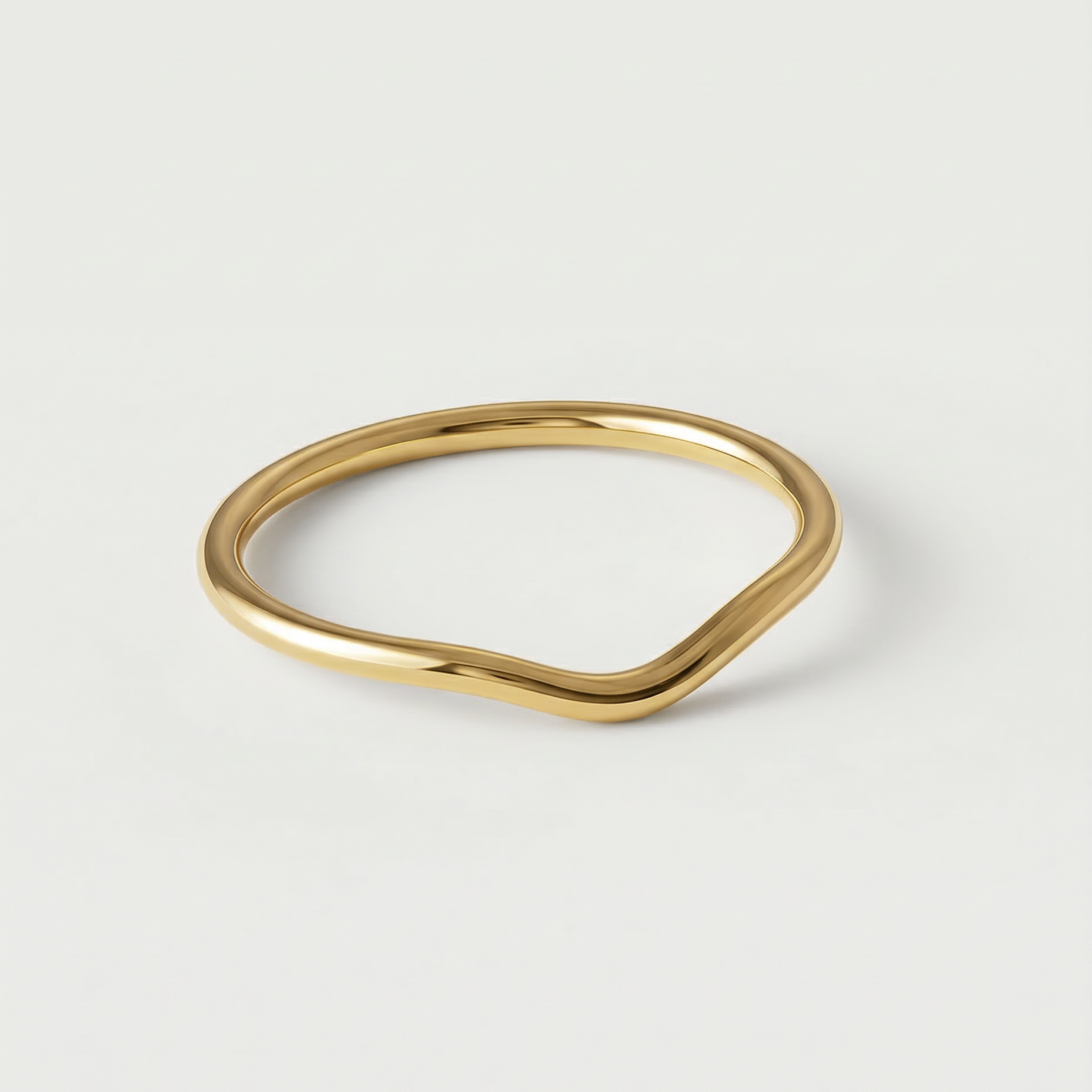 A gold-plated metal ring with a fluid, asymmetrical wave design