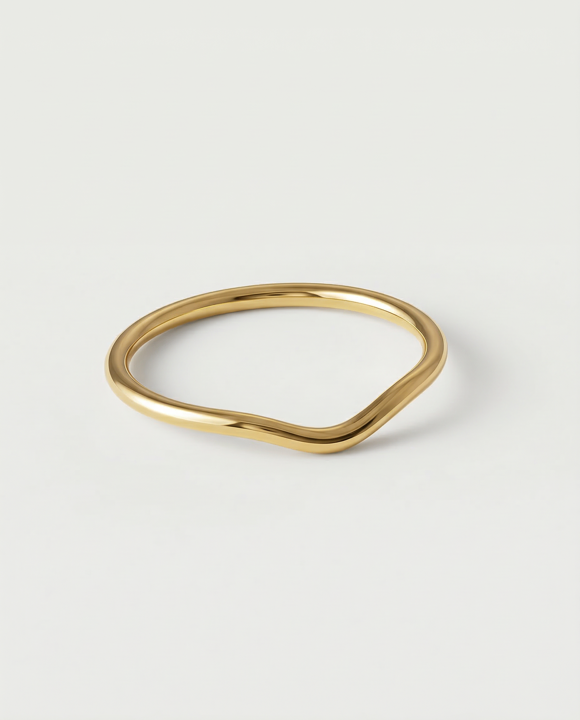 A gold-plated metal ring with a fluid, asymmetrical wave design