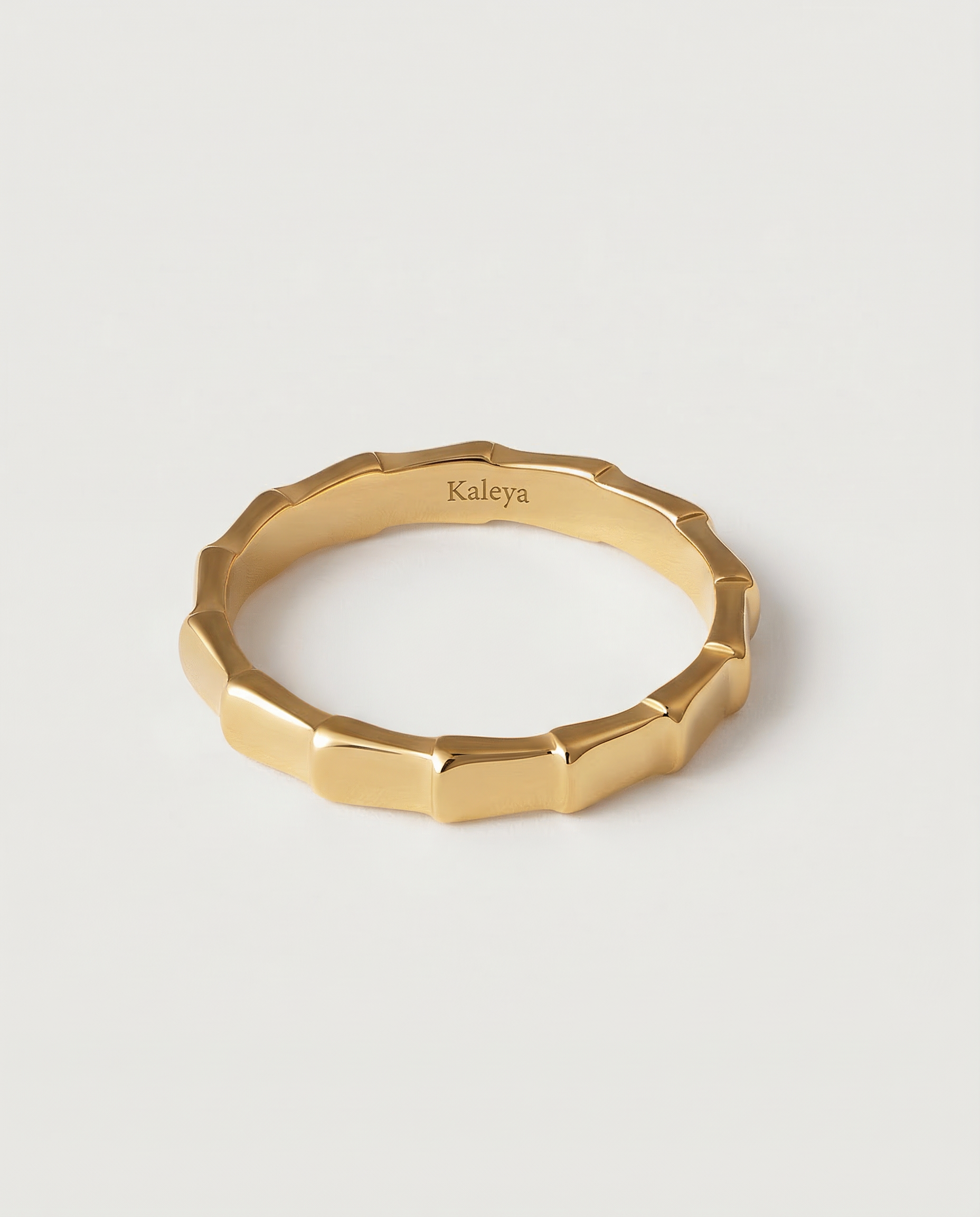A gold-plated ring with a textured surface designed to mimic bamboo segments, displayed against a white background.