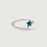 A sterling silver ring with a blue topaz star in the center, surrounded by smaller sparkling gemstones on the band, on a white background.