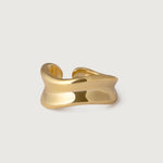 A gold-plated ring with a smooth, organic form that wraps around the finger, featuring gentle curves and hollows.