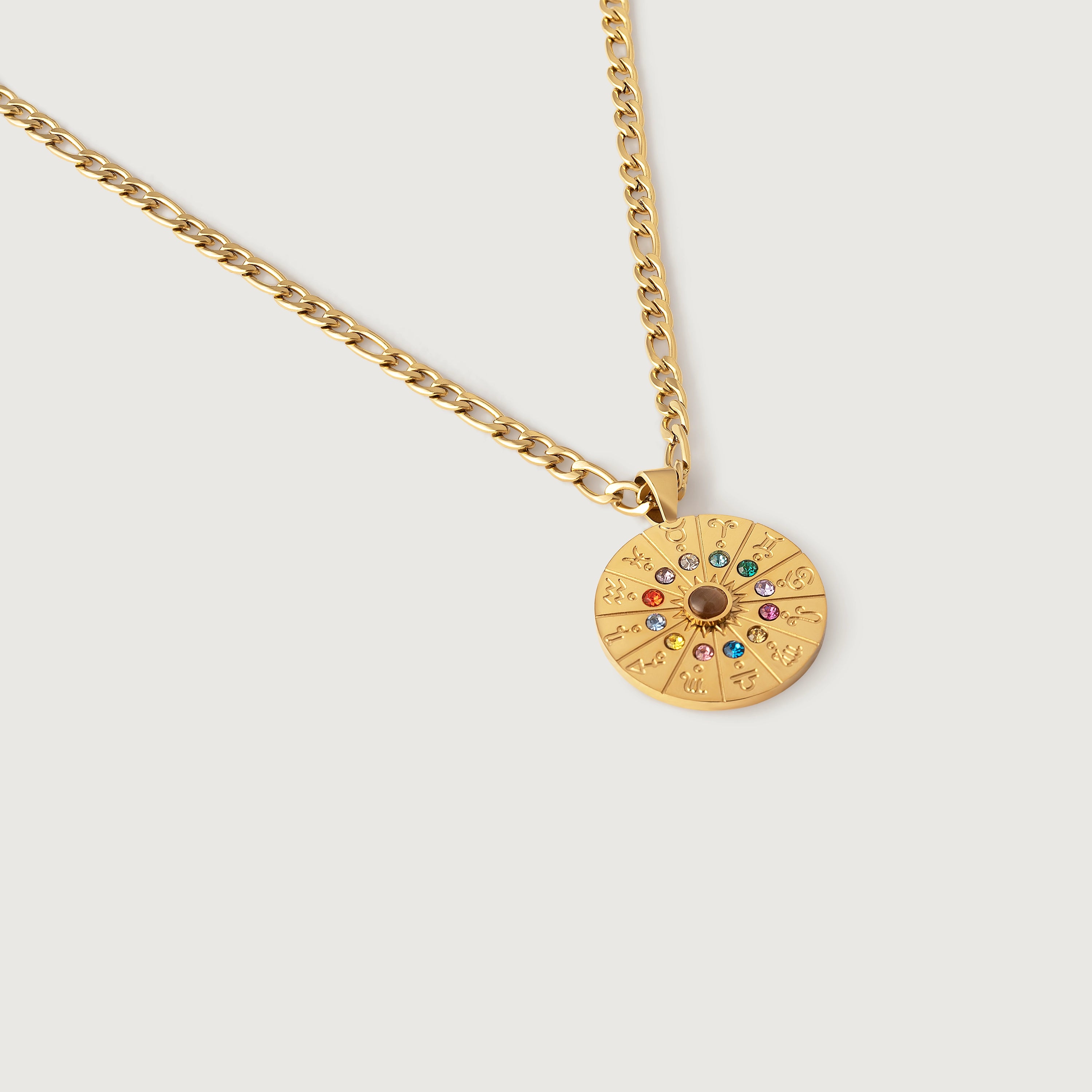 A gold-plated curb chain necklace with a round zodiac wheel pendant featuring multicolored sparkling crystals and a central moonstone.