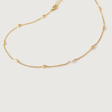 A gold-plated curb chain necklace with rectangular stations and a single pearl accent, displayed against a white background