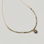 video of a gold-toned necklace with natural African turquoise beads in shades of sage, moss, and earth tones, featuring a smooth oval pendant.