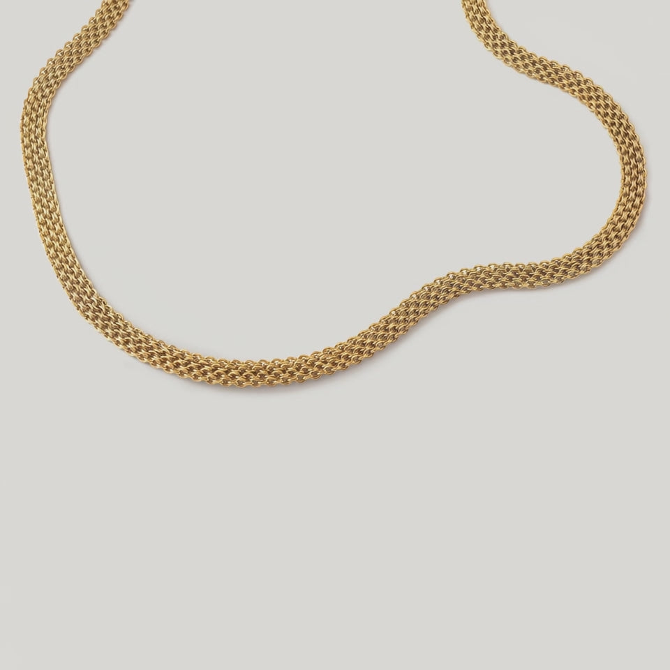 video of a gold-plated metallic mesh necklace with a fluid ribbon design