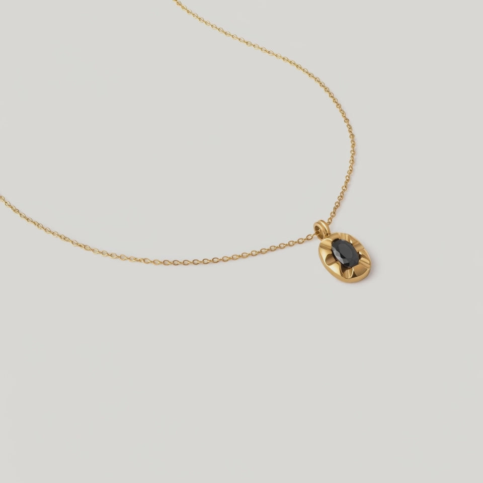 video of a gold-plated pendant necklace with a black crystal set in a sunburst frame