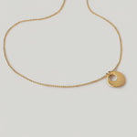 video of a gold-plated necklace with a circular charm