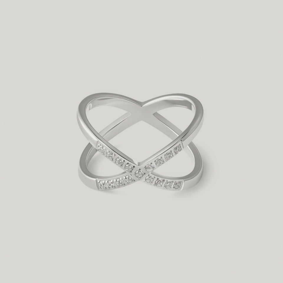 video showing a silver-colored ring with an X-shaped design and sparkling cubic zirconia stones on the intersections.