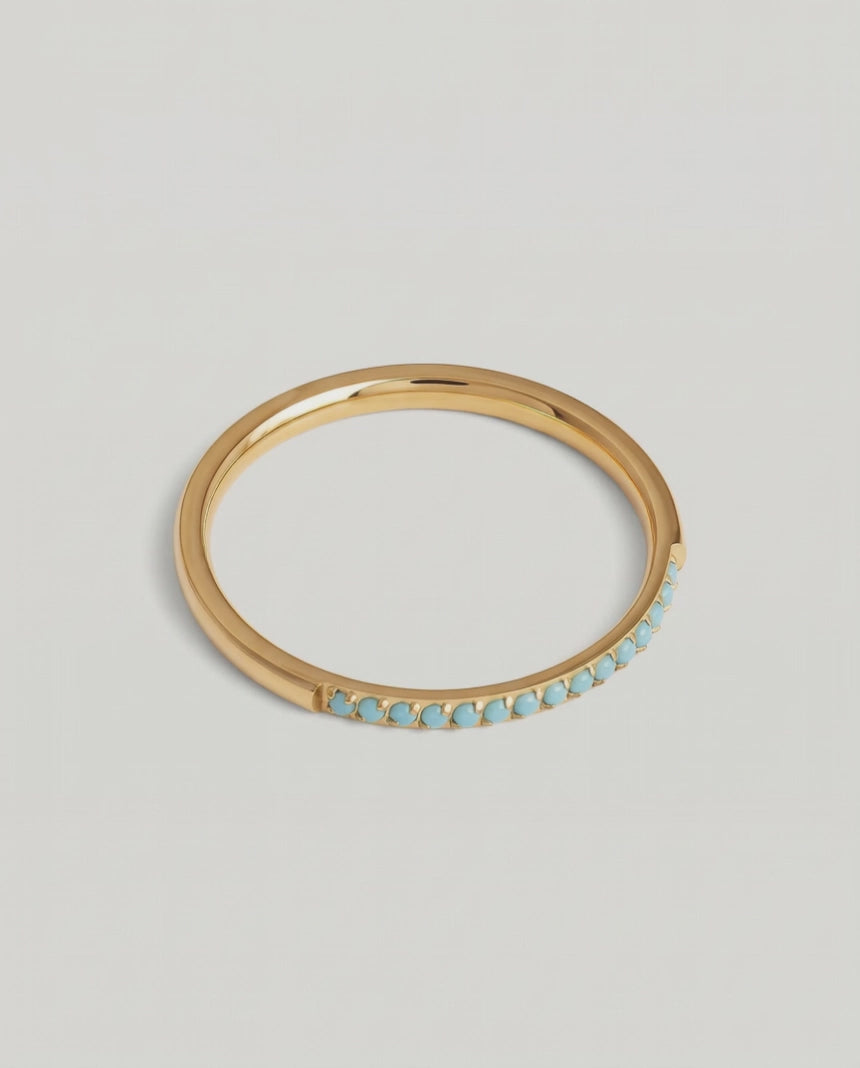 a rotating video of a minimalist gold band with a partial pavé of turquoise stones 