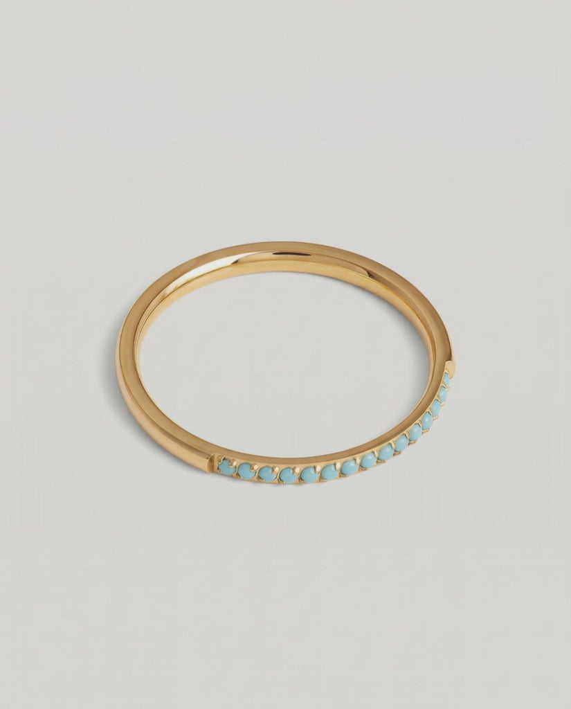 a rotating video of a minimalist gold band with a partial pavé of turquoise stones 