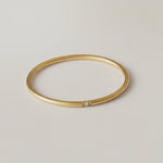 360 rotating video of a gold-colored band ring with a single sparkling stone on a white background.