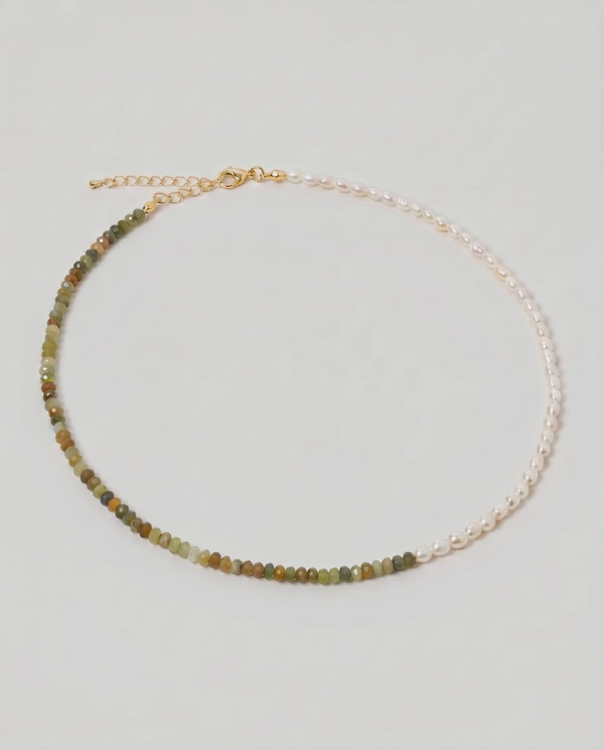 video of a multi gemstone and pearl beaded necklace in gold, with one half strung with imitation pearl rice beads and the other half with faceted mixed quartz beads in green, sage, olive