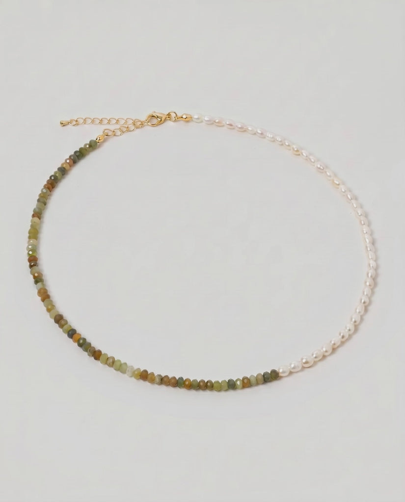 video of a multi gemstone and pearl beaded necklace in gold, with one half strung with imitation pearl rice beads and the other half with faceted mixed quartz beads in green, sage, olive
