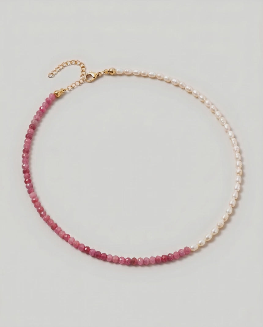 video of a  Rose quartz and pearl beaded necklace in gold, with one half strung with pearl rice beads and the other half with faceted rose quartz beads graduating from soft blush to deep pink.