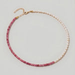 video of a  Rose quartz and pearl beaded necklace in gold, with one half strung with pearl rice beads and the other half with faceted rose quartz beads graduating from soft blush to deep pink.