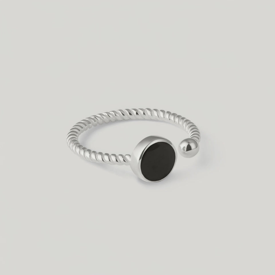 rotating vidoe of a silver ring with a twisted band and a central black onyx stone, with a small silver bead on one end.