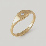 360 video of a gold signet ring with a small star-set crystal on the top, displayed against a white background.