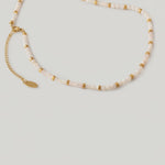 video of a milky white quartz bead necklace with petite metallic spacers, featuring a gold-colored chain as a choker.
