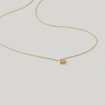 rotating video of a delicate gold-plated necklace with a hexagonal setting and a single crystal pendant.